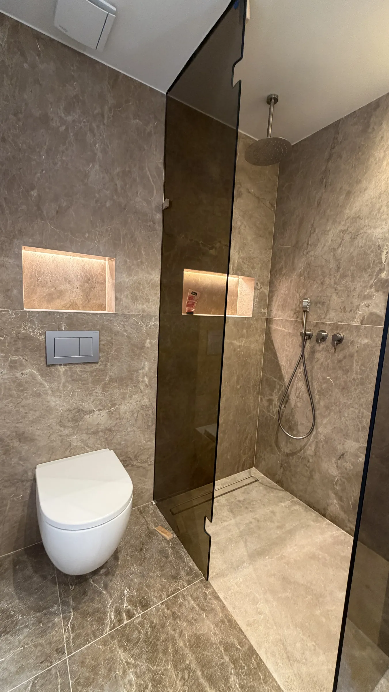 Baño revestido de piedra con mampara ahumada en una villa reformada en Cala Llamp (Port d'Andratx)