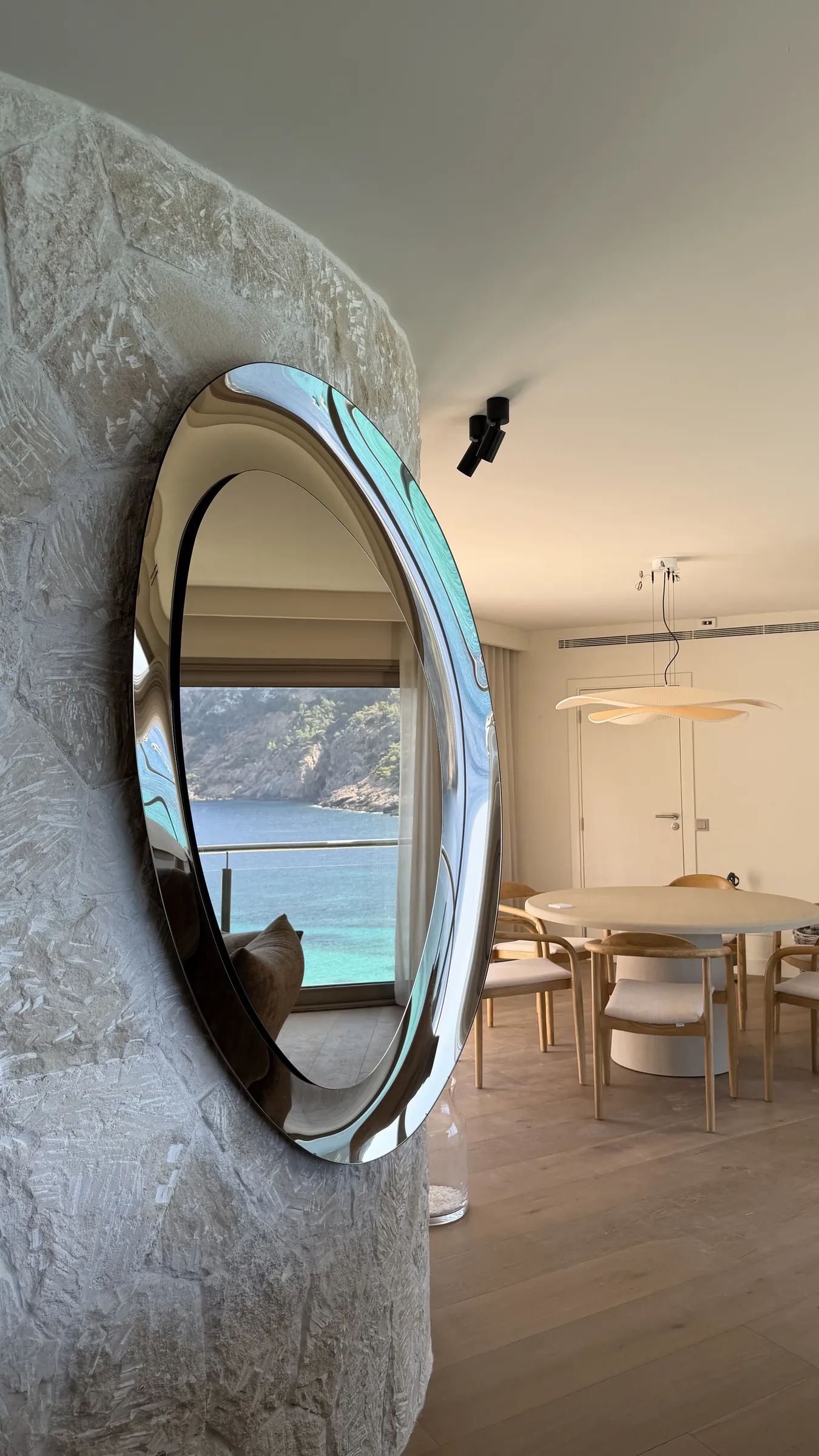 Columna de piedra con espejo y comedor en una villa reformada en Cala Llamp (Port d'Andratx)