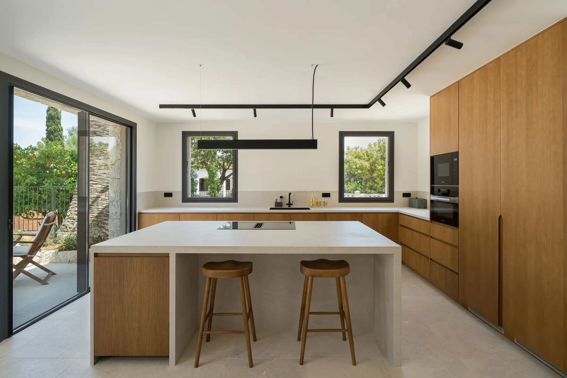 Cocina con isla de piedra y frentes de roble en la villa reformada en Es Capdellà (Calvià, Mallorca)